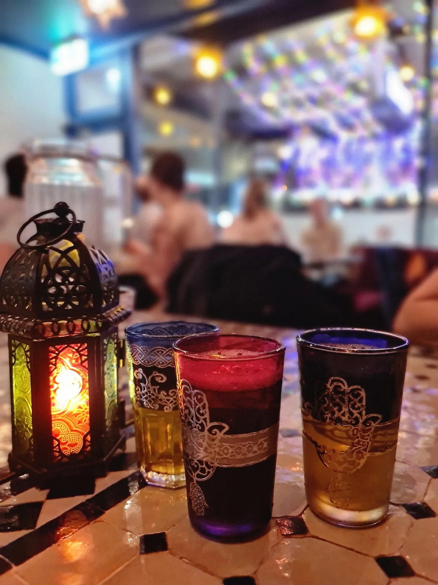 Tea glasses beside a green lantern on a Marrakech table